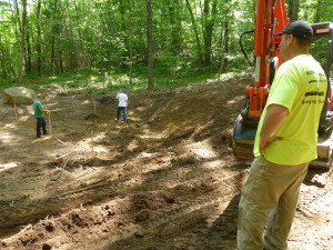 Excavator operator John Rossi (front right) watches Dan Borelli and Jake Merloni (back left and center, respectively) take measurements during ground preparation for Illuminating Futures memorial garden by Borelli on May 28, 2016. Photo by Marie Cieri.